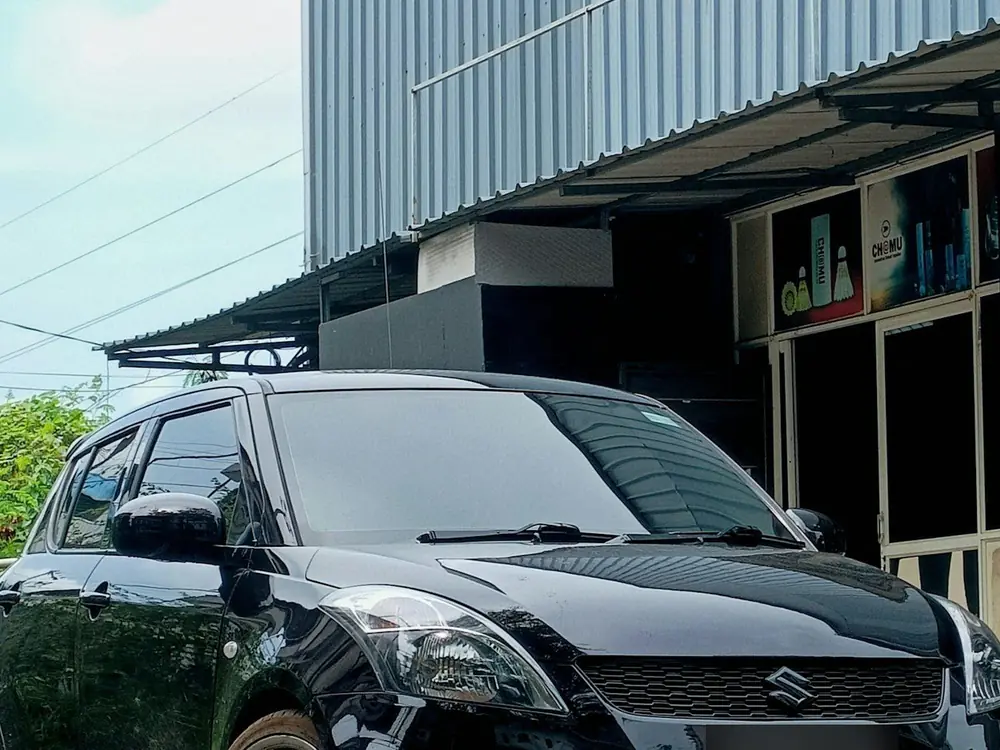 Black Maruti Suzuki Swift parked outside a shop